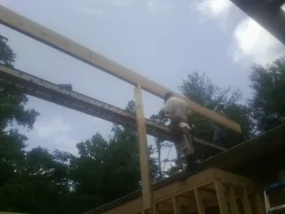 Carpenter setting a ridge beam over a new addition frame — Ice Dam Removal by Roofing Brothers in Patton