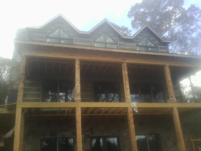 Dormers and porch framing on a large log home under construction — Roof Coating work by our crew in Patton