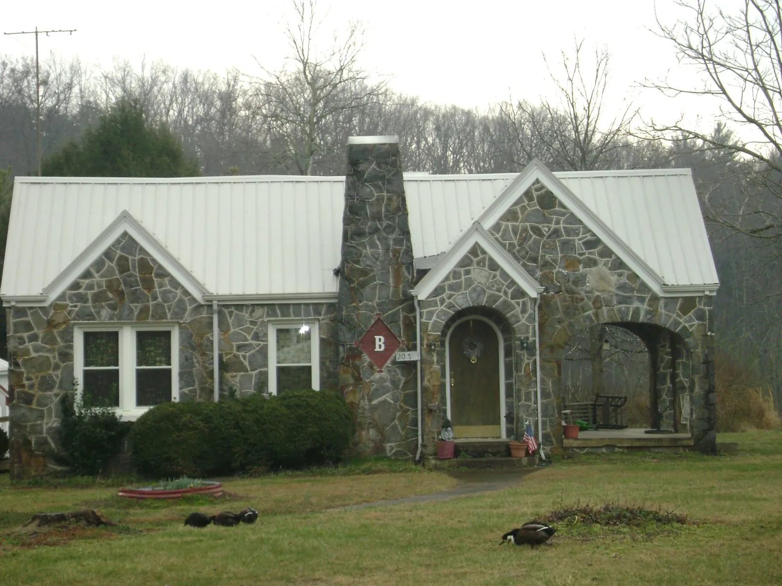 White metal roof on a stone cottage with steep gables in Patton