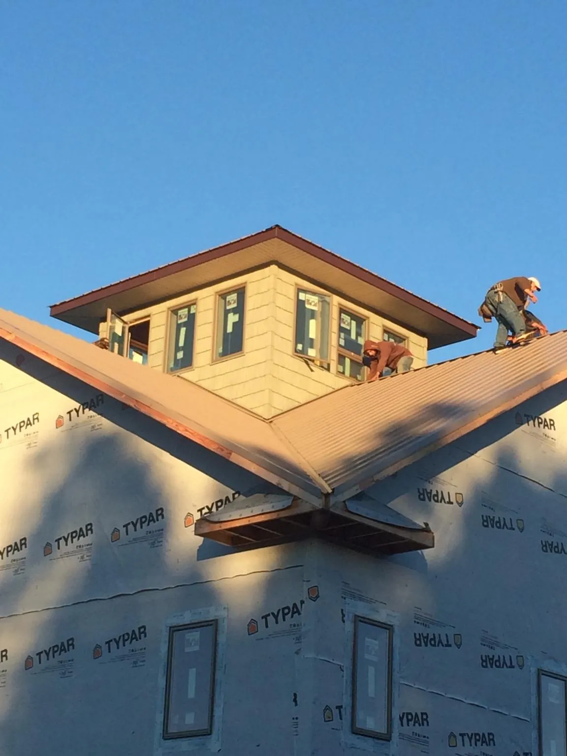 Roofers working around a rooftop cupola on a new metal roof at sunset — Roof Waterproofing in Patton by Roofing Brothers